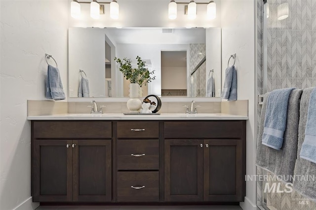 bathroom with double vanity, tiled shower, a sink, and visible vents