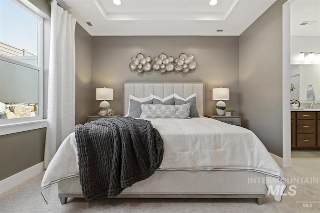 bedroom with recessed lighting, a tray ceiling, light colored carpet, and baseboards