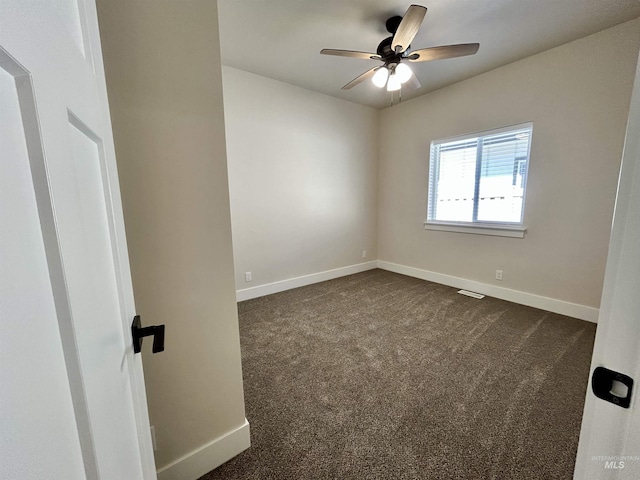 empty room with dark carpet, baseboards, and a ceiling fan