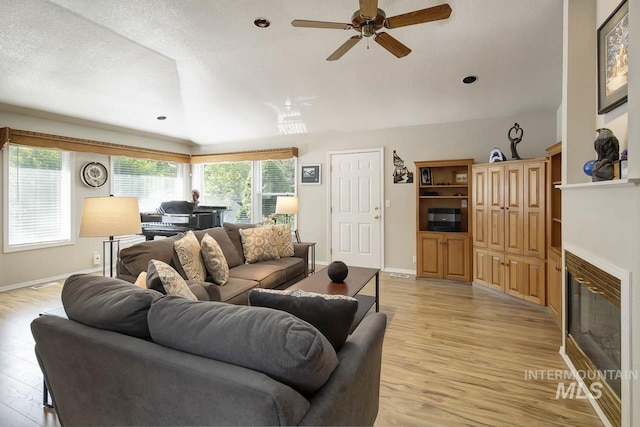 3411 Wilson Ln, Nampa, ID 83686 - living area with a ceiling fan, light wood finished floors, a glass covered fireplace, baseboards, and lofted ceiling