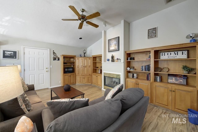 3411 Wilson Ln, Nampa, ID 83686 - living area featuring a glass covered fireplace, a ceiling fan, vaulted ceiling, and light wood-style flooring