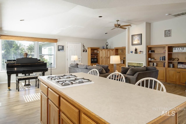 3411 Wilson Ln, Nampa, ID 83686 - kitchen with lofted ceiling, a ceiling fan, light wood finished floors, a kitchen island, and white gas stovetop