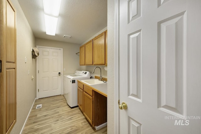 3411 Wilson Ln, Nampa, ID 83686 - laundry room featuring cabinet space, light wood-type flooring, washer and clothes dryer, a textured ceiling, and baseboards
