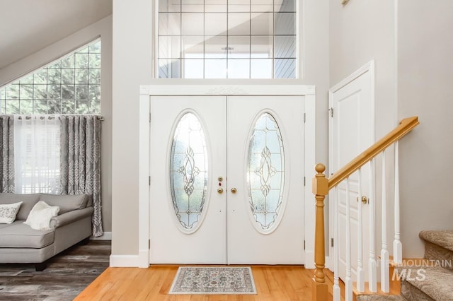 foyer entrance with french doors, stairway, a high ceiling, and wood finished floors