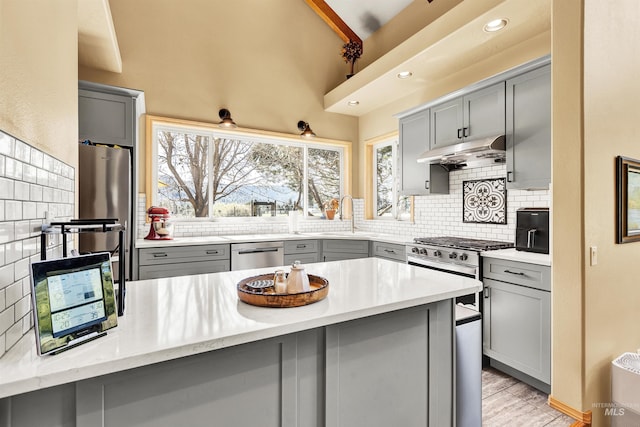 kitchen featuring gray cabinets, under cabinet range hood, dishwasher, and recessed lighting