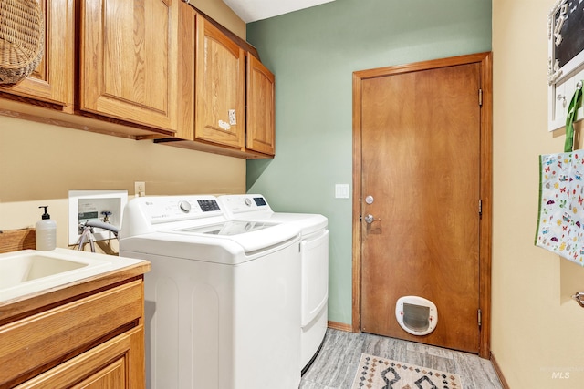 washroom with washer and clothes dryer, cabinet space, light wood-type flooring, and baseboards