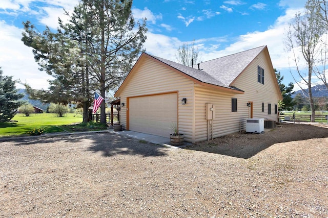 view of property exterior with a shingled roof, fence, cooling unit, and dirt driveway