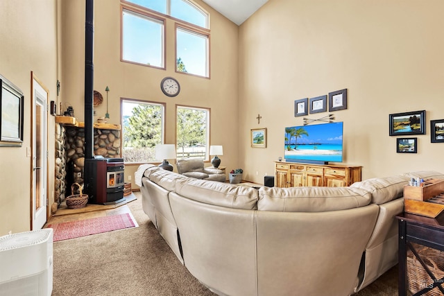 carpeted living area with a wood stove, a towering ceiling, and plenty of natural light
