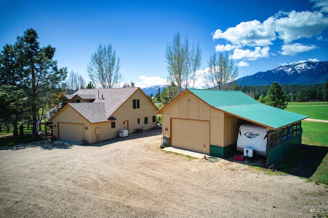 view of front of home with a mountain view, a detached garage, board and batten siding, and an outbuilding