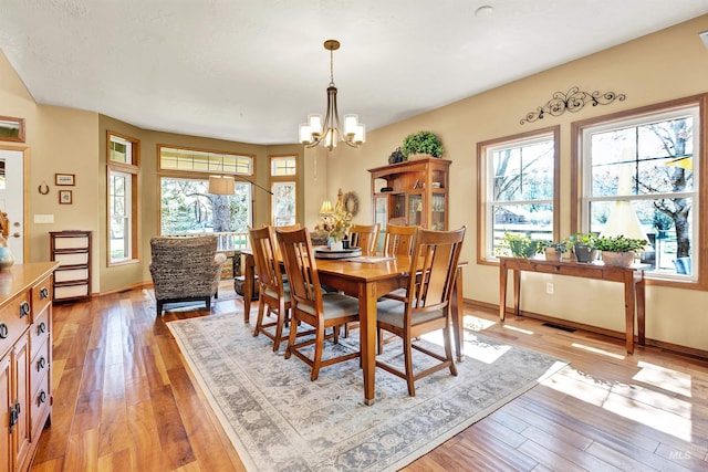 dining area with light wood-style floors, baseboards, and a chandelier