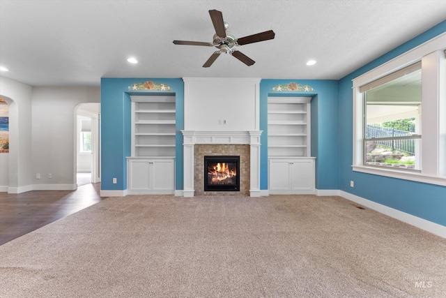 1031 E Reflect Ridge Dr, Meridian, ID 83642 - unfurnished living room featuring carpet, ceiling fan, a tiled fireplace, baseboards, and arched walkways