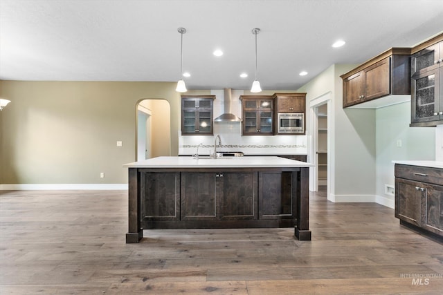 1031 E Reflect Ridge Dr, Meridian, ID 83642 - kitchen with wall chimney exhaust hood, stainless steel microwave, baseboards, a kitchen island with sink, and light countertops
