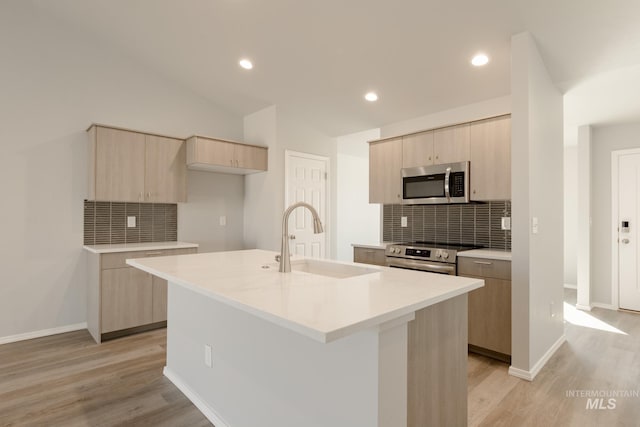 kitchen with sink, a center island with sink, light hardwood / wood-style flooring, and appliances with stainless steel finishes