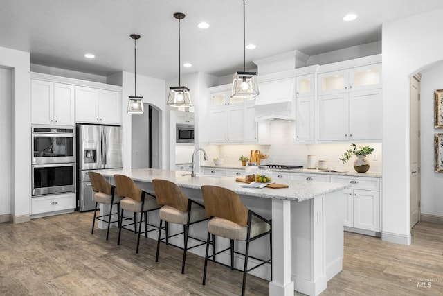 5853 W Venetian Dr, Eagle, ID 83616 - kitchen with stainless steel appliances, arched walkways, a sink, backsplash, and an island with sink