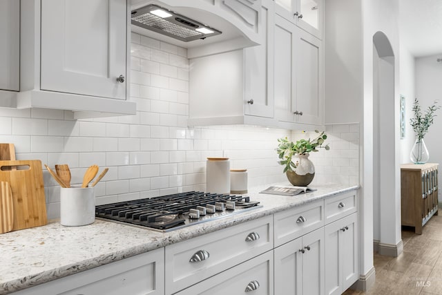 5853 W Venetian Dr, Eagle, ID 83616 - kitchen with stainless steel gas stovetop, under cabinet range hood, white cabinets, and arched walkways