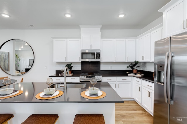 kitchen featuring sink, a breakfast bar area, appliances with stainless steel finishes, light hardwood / wood-style floors, and white cabinets