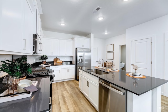 kitchen featuring sink, white cabinets, a kitchen island with sink, stainless steel appliances, and light hardwood / wood-style flooring