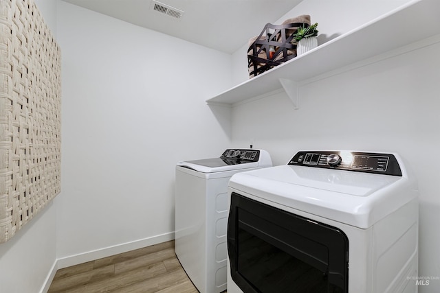 laundry room with light hardwood / wood-style flooring and washer and dryer