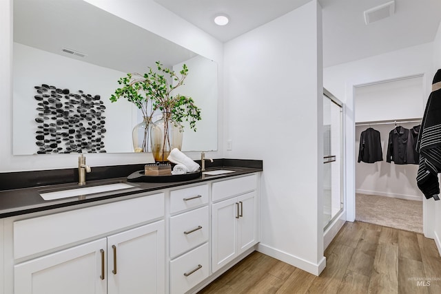 bathroom with vanity, hardwood / wood-style floors, and a shower with door