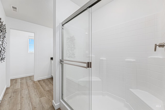 bathroom with a shower with shower door and wood-type flooring