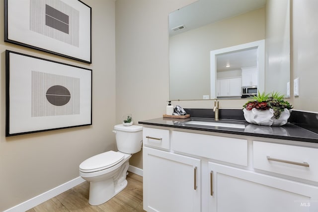 bathroom with hardwood / wood-style flooring, vanity, and toilet