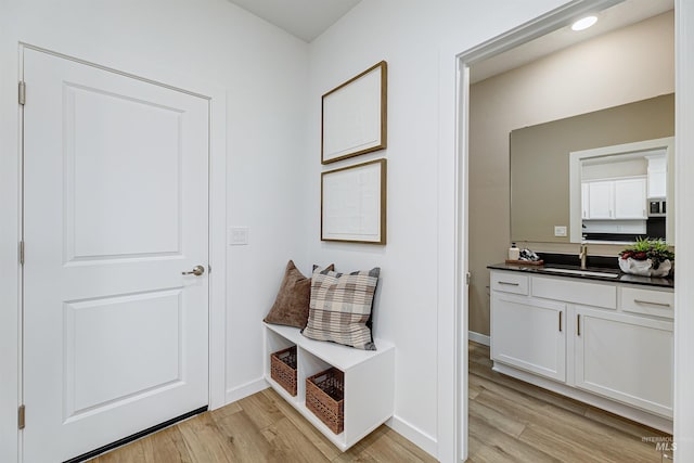 mudroom with sink and light hardwood / wood-style flooring