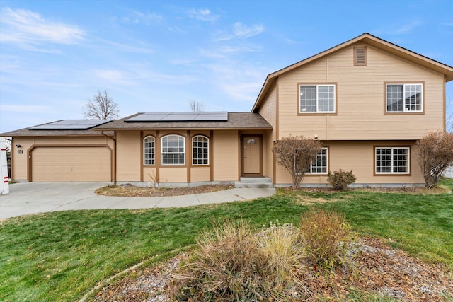 tri-level home featuring solar panels, a garage, and a front lawn