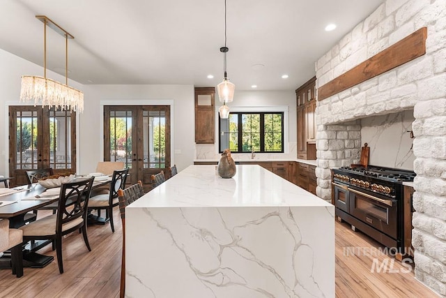 1195 N Arrano Farms Ln, Eagle, ID 83616 - kitchen with french doors, double oven range, light wood-type flooring, a kitchen island, and recessed lighting