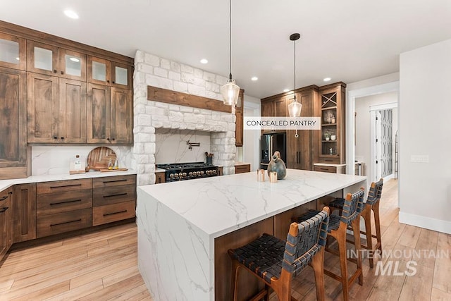 1195 N Arrano Farms Ln, Eagle, ID 83616 - kitchen with a center island, stainless steel appliances, light wood-style floors, a kitchen breakfast bar, and glass insert cabinets