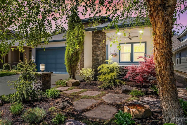 view of front of home with a garage, stucco siding, driveway, and stone siding