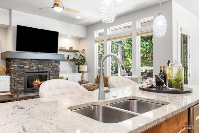 kitchen featuring a sink, light stone countertops, a fireplace, and decorative light fixtures