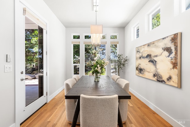 dining space with a healthy amount of sunlight, light wood finished floors, and a notable chandelier