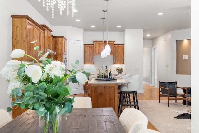 kitchen featuring pendant lighting, a kitchen island, a kitchen breakfast bar, brown cabinets, and light wood-style flooring