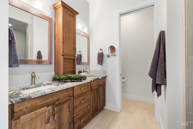 full bath with double vanity, a sink, and baseboards
