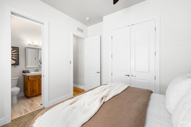 bedroom featuring baseboards, visible vents, ensuite bathroom, and a closet