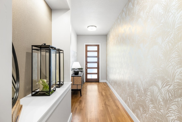 doorway featuring baseboards and light wood finished floors