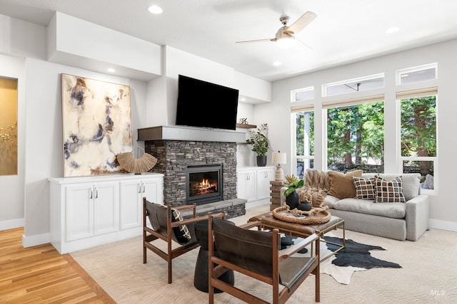 living room featuring ceiling fan, a fireplace, recessed lighting, baseboards, and light wood-type flooring