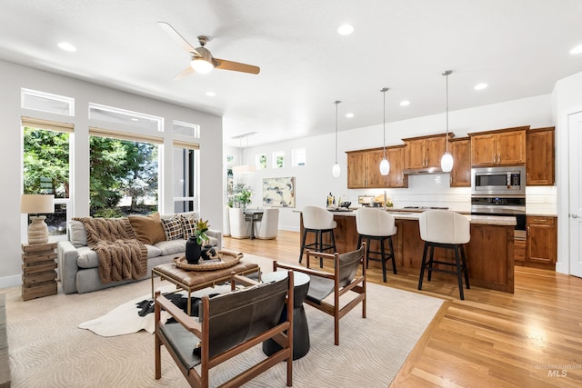living area with recessed lighting, baseboards, ceiling fan, and light wood-type flooring