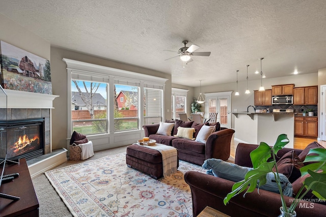 living area featuring a textured ceiling, a ceiling fan, and a fireplace
