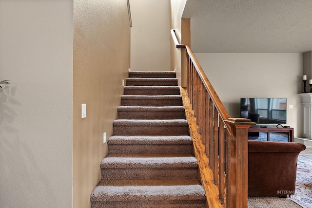 staircase with carpet floors and a textured ceiling