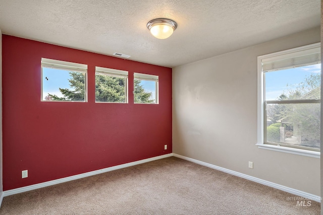 empty room featuring a textured ceiling, baseboards, carpet, and visible vents