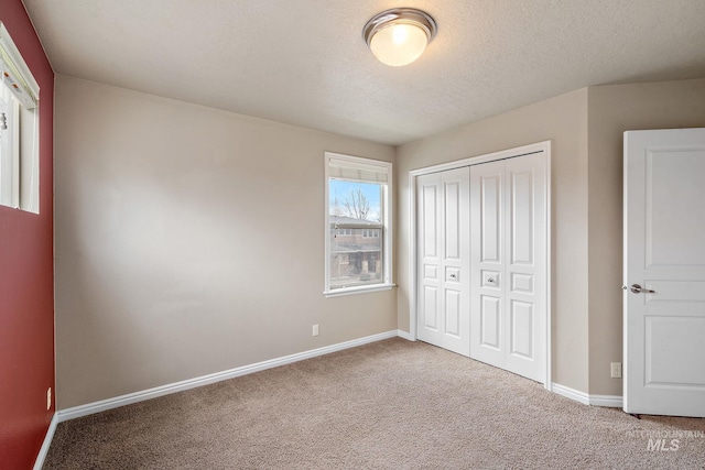 unfurnished bedroom with carpet floors, baseboards, a closet, and a textured ceiling
