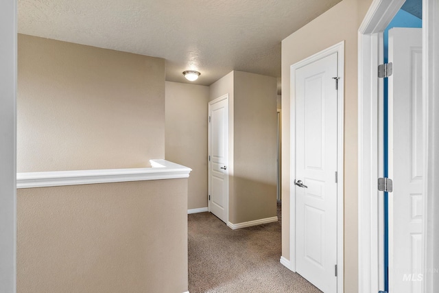 corridor featuring baseboards, carpet flooring, and a textured ceiling