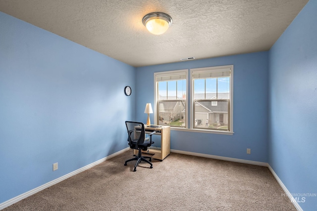 unfurnished office featuring visible vents, baseboards, a textured ceiling, and carpet floors