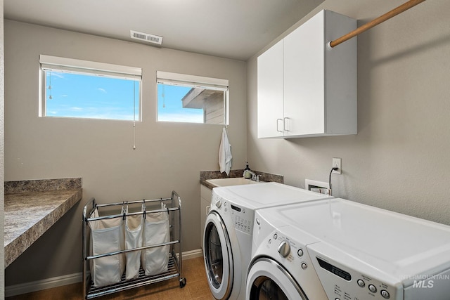 laundry area with baseboards, visible vents, independent washer and dryer, cabinet space, and a sink