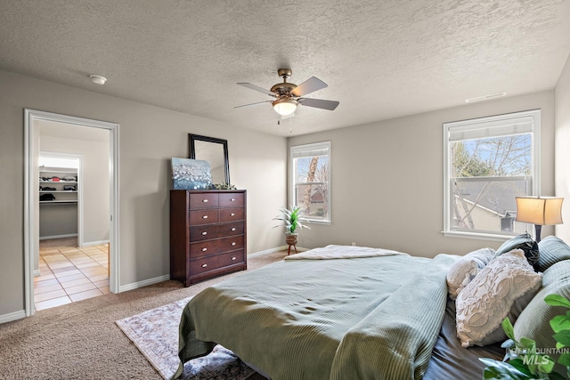 carpeted bedroom featuring visible vents, a textured ceiling, multiple windows, and a ceiling fan