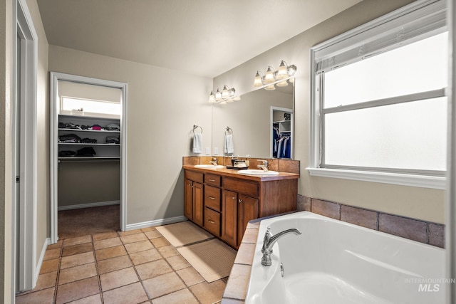 full bathroom with a walk in closet, double vanity, a bath, and a sink