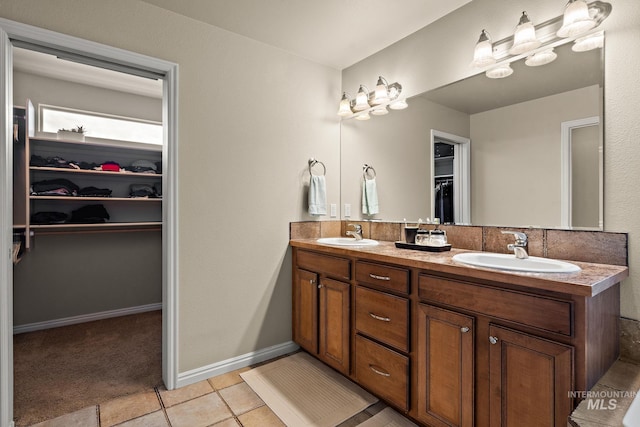 full bathroom featuring a sink, a spacious closet, double vanity, and tile patterned flooring