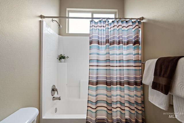 full bath featuring toilet, shower / bathtub combination with curtain, and a textured wall