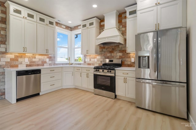 4320 SW 2nd Ave, New Plymouth, ID 83655 - kitchen with appliances with stainless steel finishes, premium range hood, light countertops, light wood-style floors, and white cabinetry
